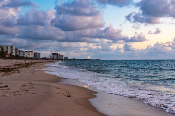 an early morning at the beach with the pier and lighthouse in the background