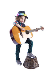 Cute little boy in black cowboy hat learns to play the guitar.The boy sings to the guitar. Boy puts his foot on the basket. White background.