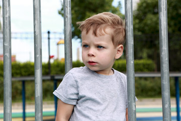 Serious boy on fence background