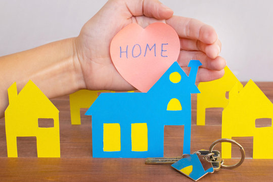 Buying or renting new house concept, colorful paper houses and keys on the wooden background.