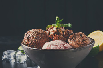 Portion of ice cream scoops with fruit on black