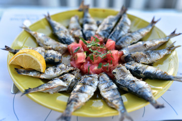 Greek cuisine, Plate of grilled sardines served with tomato, onion and lemon slice