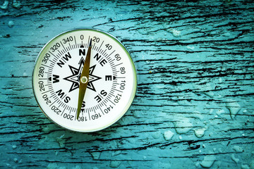 compass on old wood table with rain drops, find the right direction concept, flat top view