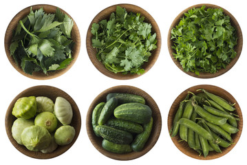 Top view. Fresh green vegetables and herbs isolated on a white background. Squash, green peas, cucumbers and leaves parsley, celery, cilantro in wooden bowl with copy space for text.