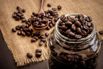 Coffee bean grain in a glass bottle on black table with sack fabric