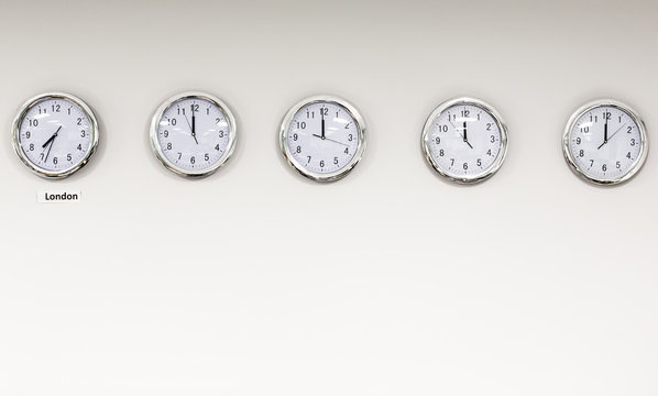 Modern quarz analog clocks on white wall in office