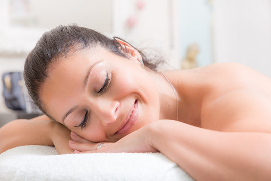 Junge Frau liegt auf einem Massagetiesch und lächelt entspannt