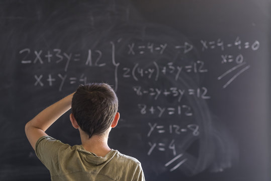 Schoolboy Solving A Problem On A Blackboard.