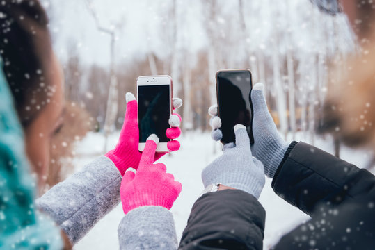 Couple Using Smartphone In Winter With Gloves For Touch Screens