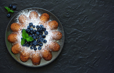 Vanilla cake (gugelhupf) with blueberries. dark background.