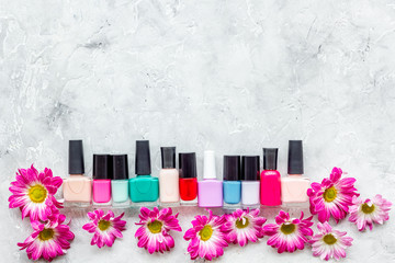 Choose nail polish for manicure. Bottles of colored polish on grey background top view copyspace