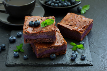 Chocolate brownies with blueberries and cream filling. Dark background.