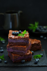 Chocolate brownies with blueberries and cream filling. Dark background.