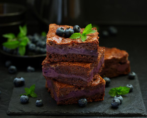 Chocolate brownies with blueberries and cream filling. Dark background.