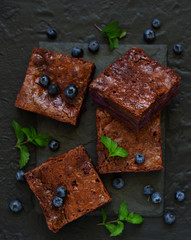 Chocolate brownies with blueberries and cream filling. Dark background.