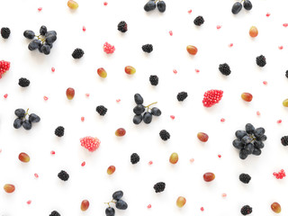 Concept of healthy food. Berries and fruit pattern. Blackberries, grains of pomegranate, black and green grapes on a white background.Composition of berries and fruits, top view.