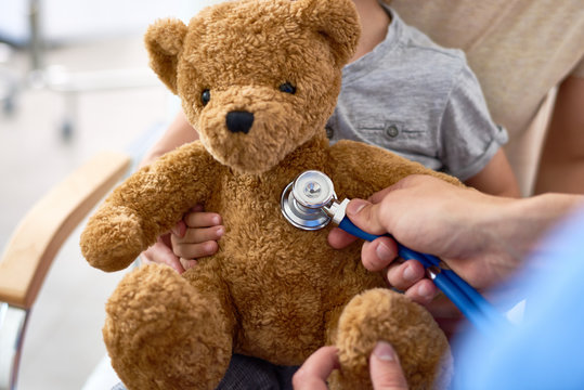 Close-up shot of unrecognizable doctor using stethoscope in order to examine teddy bear belonging to little patient