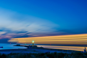 night view of lighthouse of Warnemuende on the Baltic Sea at the harbor with light stripes from...