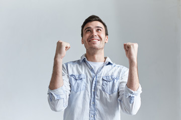 Joy, victory, celebration, triump and excitement concept. Picture of euphoric ecstatic student celebrating his success and education achievement, clenching fists, feeling happy and excited, saying Yes