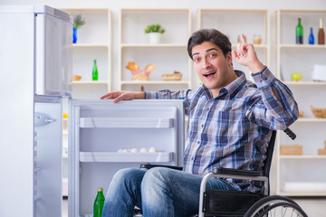 Naklejka na ściany i meble Young disabled injured man opening the fridge door 