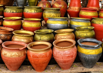 Fototapeta na wymiar Clay pots stacked for sale on African roads. Pottery making place. Local craft market in Africa. Unique handmade colorful ceramic pots. Craftsmanship. African style.