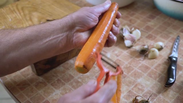 man is cleaning carrots close-up