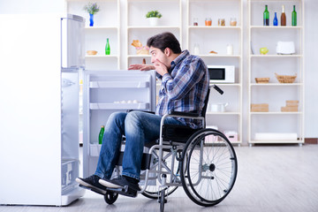 Fototapeta na wymiar Young disabled injured man opening the fridge door 
