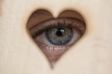 An eye looking through a wooden heart