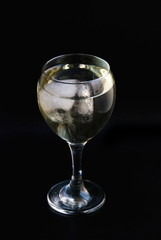 A glass of white wine with ice cube