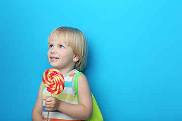 Portrait of little boy with lollipop on blue background