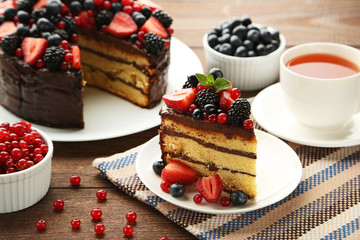 Piece of chocolate cake with berries in plate on wooden table