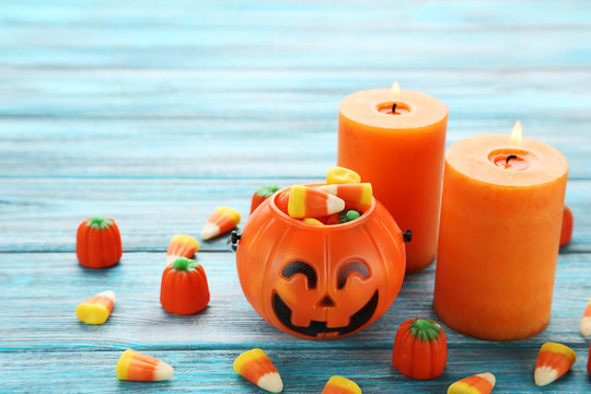 Halloween candy corns in basket with candles on wooden table