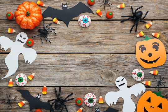 Halloween bats, spiders, ghosts and candies on grey wooden table