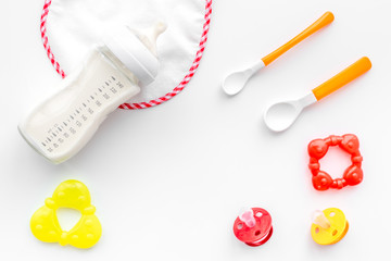 preparation of mixture baby feeding with infant formula powdered milk in bottle with bib on white background top view
