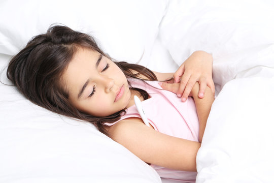 Sick little girl with thermometer in white bed