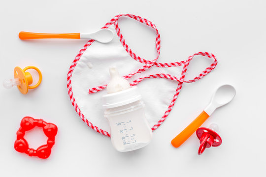 preparation of mixture baby feeding with infant formula powdered milk in bottle with bib on white background top view