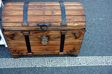 Коричневый закрытый деревянный сундук стоит на асфальте во дворе