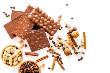 Preparing chocolate. Chocolate bars, nuts, cinnamon on white background top view copyspace