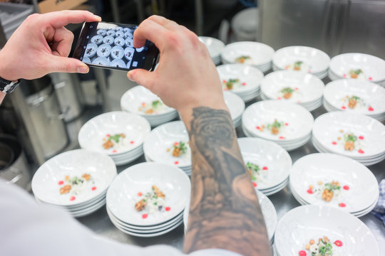 Chef photographing savory dish with a mobile phone for advertising catering services