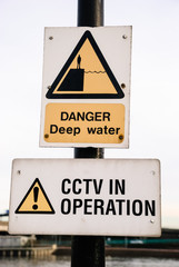 Signs at a harbour warning about deep water, and that CCTV is in operation
