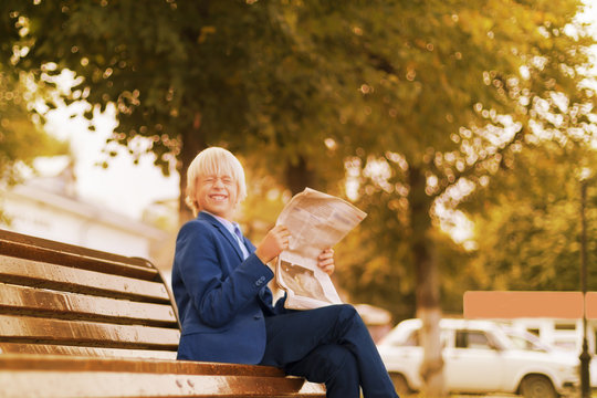 Autumn, Boy In The Park Reading A Newspaper