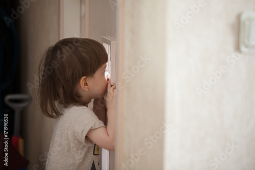 The Little Boy Looks In The Window Of The Door A Child