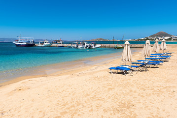 Obraz premium Sunbeds on sandy beach of Agia Anna ,one of the busiest beaches of Naxos. Cyclades, Greece.