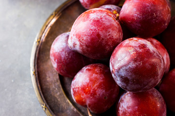Ripe Juicy Colorful Red Organic Plums on Vintage Metal Plate. Dark Stone Background. Copy Space. Autumn Fall Harvest Thanksgiving.