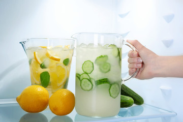 Female hand taking jug of cucumber lemonade from fridge