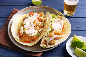 Plate with tasty fish tacos on wooden table