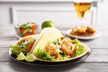 Plate with tasty fish tacos on wooden table
