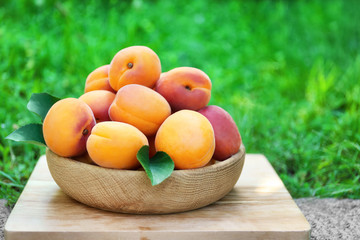 Juicy apricots in bowl on stand outdoor