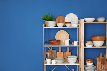 Fototapeta na wymiar Kitchen shelving with dishes on blue wall background