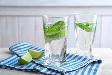 Fotobehang Glasses with basil water on table © Africa Studio